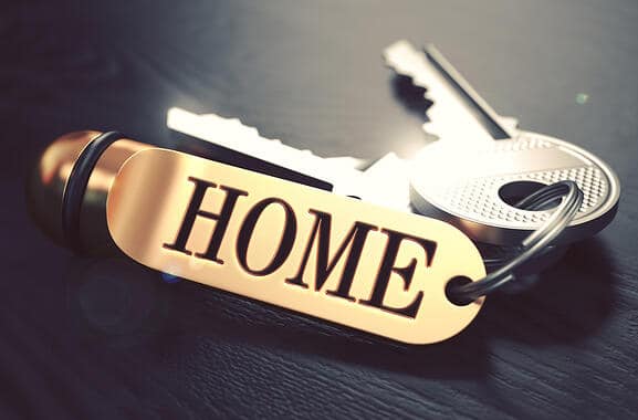 Keys and Golden Keyring with the Word Home over Black Wooden Table with Blur Effect. Toned Image.